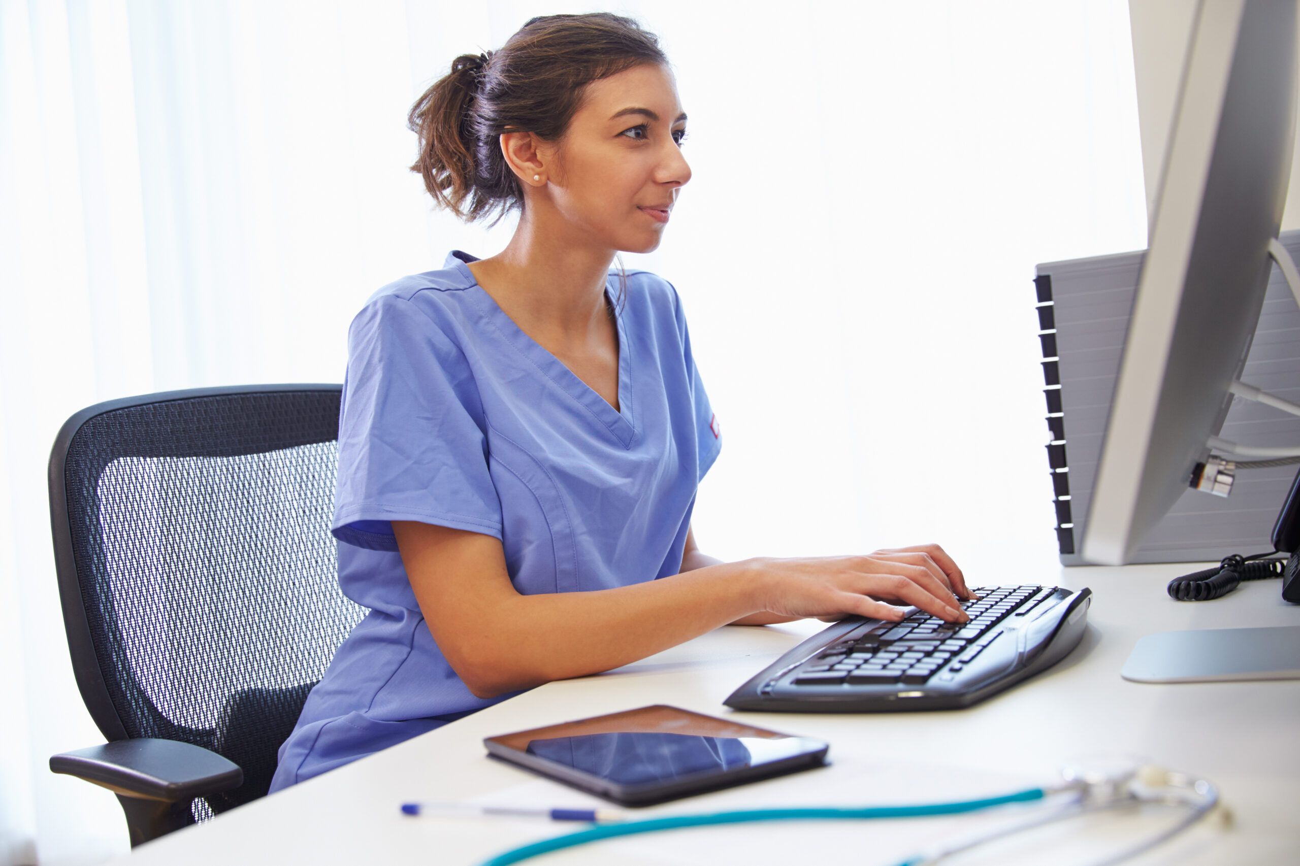 Young adult indian student woman taking notes while using laptop at home