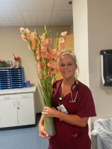 Jessica Barker, Uniti Med DAISY Award Honoree, holding flowers. 