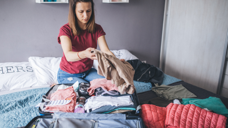 Healthcare traveler packing essentials in suitcase for travel assignment