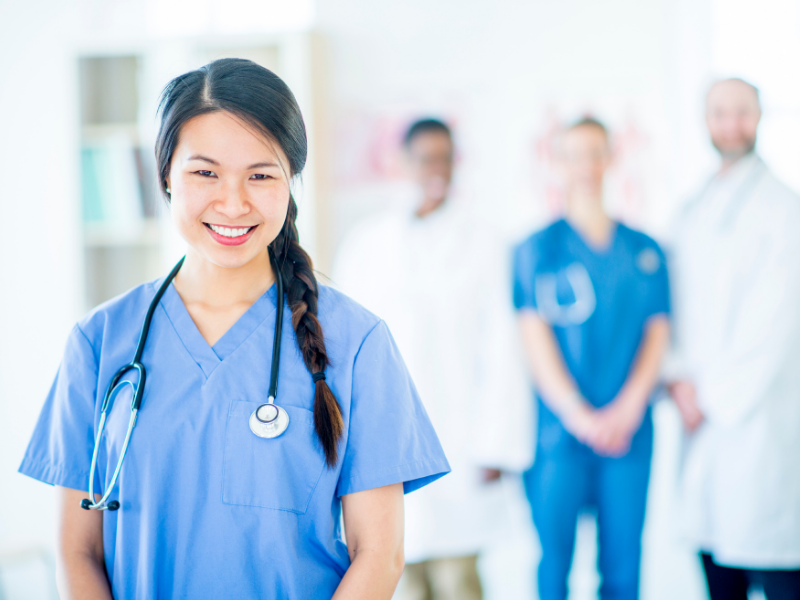 Travel nurse with doctors standing behind her